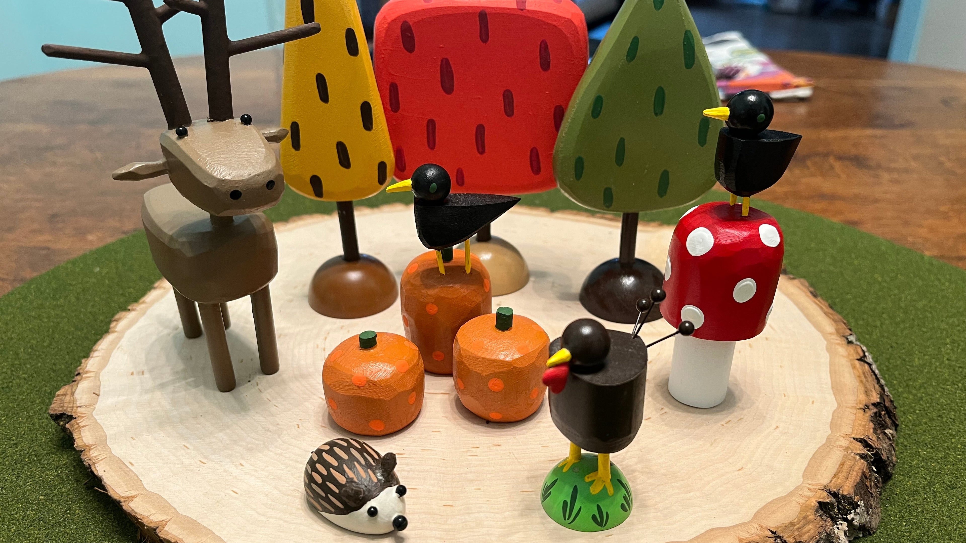 Wooden animal figurines on a wooden base with a forest-themed design.